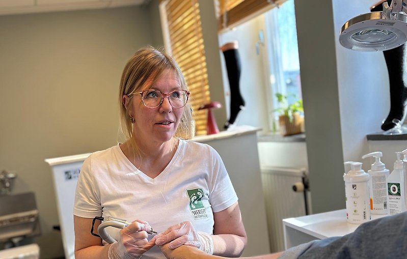 Kvinnlig fotvårdare håller i fot. 